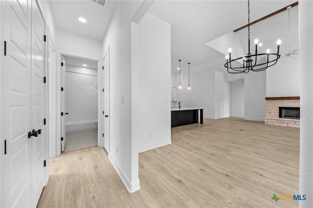 hallway with baseboards, recessed lighting, a notable chandelier, and light wood-style floors