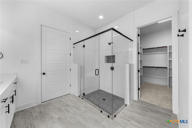 full bathroom featuring a shower stall, vanity, and a walk in closet