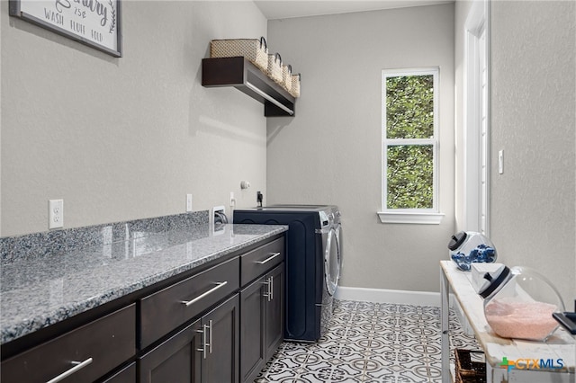 laundry room with washer and clothes dryer, cabinets, and light tile patterned floors