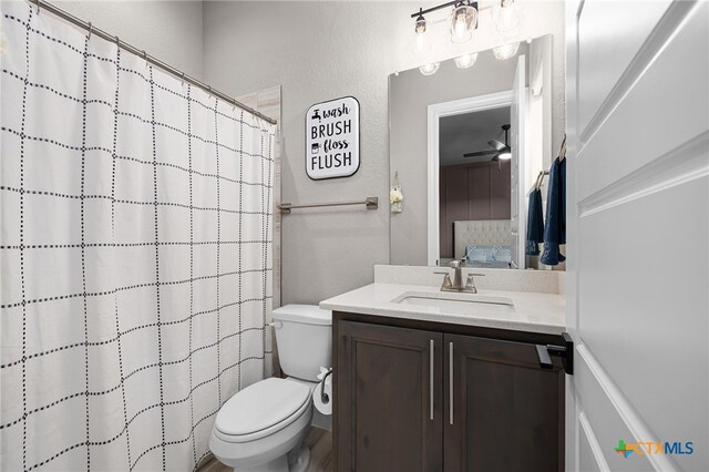 bathroom featuring toilet, ceiling fan, vanity, and walk in shower