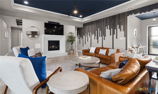 living room with ceiling fan and a tray ceiling