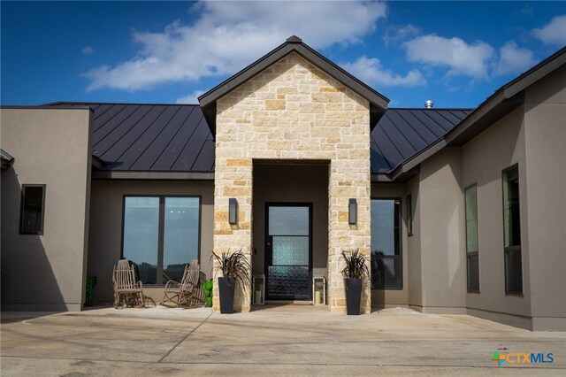 view of exterior entry with a patio area