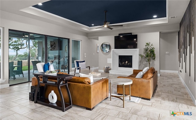 living room with ceiling fan and a tray ceiling