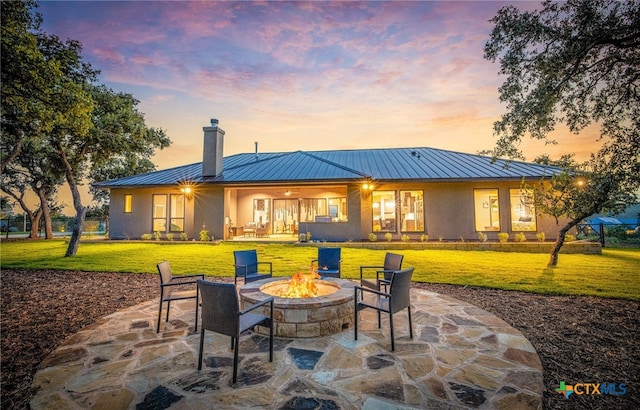 back house at dusk featuring an outdoor fire pit, a yard, and a patio area