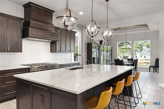 kitchen featuring a kitchen breakfast bar, sink, a spacious island, and decorative light fixtures