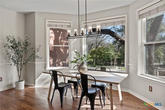 dining space with a chandelier, wood finished floors, and baseboards