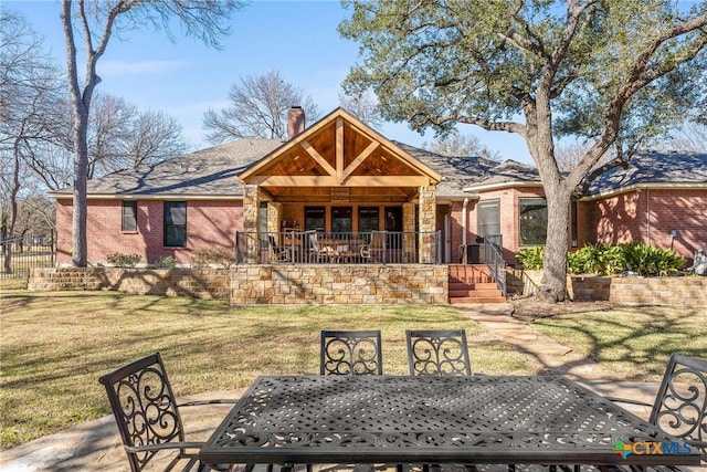 view of front facade with brick siding, a chimney, a patio area, a front lawn, and outdoor dining space