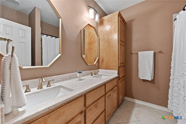 bathroom featuring tile patterned flooring, visible vents, a sink, and baseboards