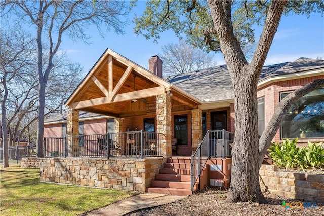 view of front of property featuring a porch, a shingled roof, and a chimney