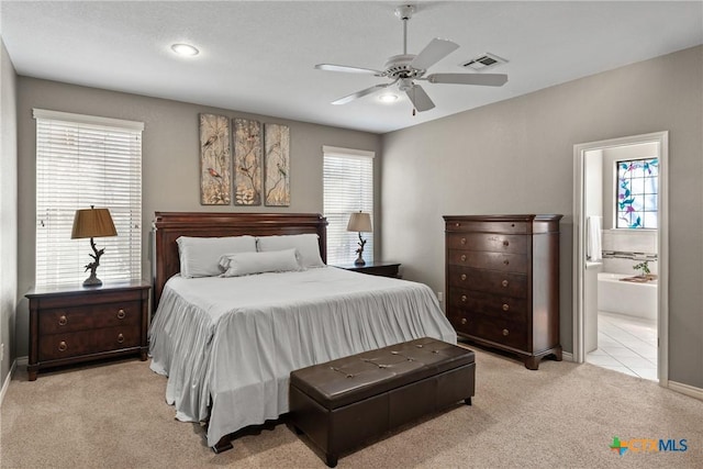 bedroom featuring connected bathroom, light colored carpet, a ceiling fan, baseboards, and visible vents