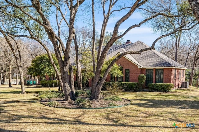 view of property exterior featuring roof with shingles, brick siding, a yard, a chimney, and central air condition unit