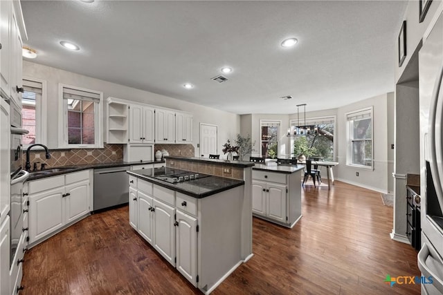 kitchen with dishwasher, a kitchen island, black electric stovetop, open shelves, and a sink