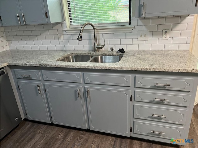 kitchen featuring a sink, backsplash, stainless steel dishwasher, gray cabinetry, and dark wood-style floors