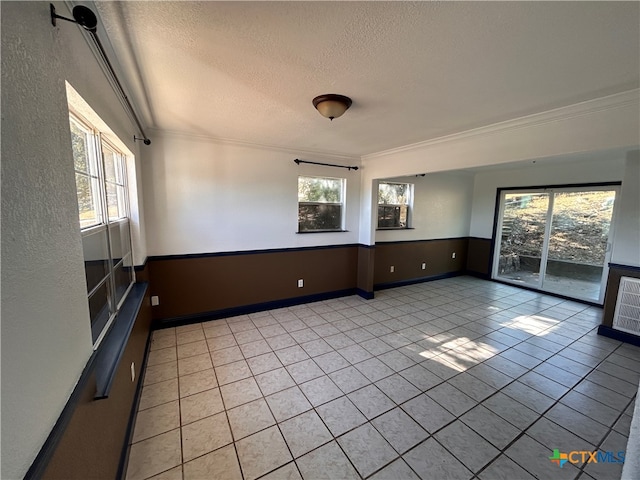 unfurnished room with ornamental molding, plenty of natural light, a textured ceiling, and light tile patterned floors