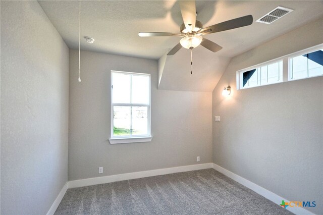 carpeted spare room featuring visible vents, baseboards, attic access, and a ceiling fan