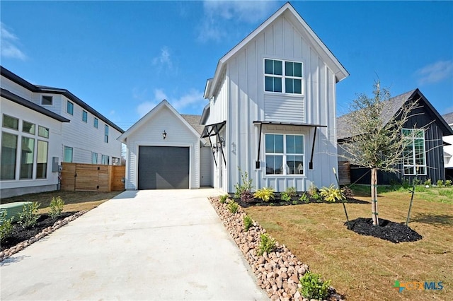 modern farmhouse style home featuring board and batten siding, fence, a garage, an outbuilding, and driveway