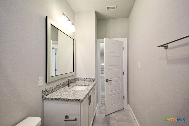 bathroom featuring vanity, toilet, baseboards, and visible vents