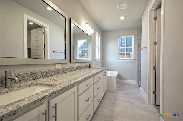 bathroom featuring a shower stall, a freestanding tub, visible vents, and a sink