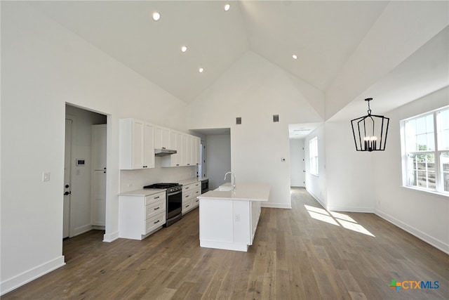 kitchen featuring hardwood / wood-style flooring, white cabinetry, hanging light fixtures, stainless steel range with gas stovetop, and a center island with sink