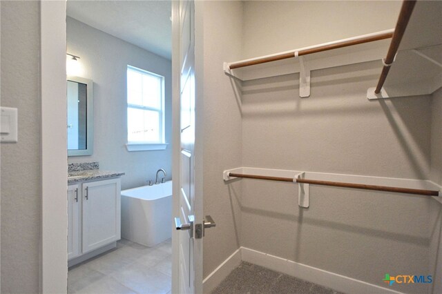 full bathroom featuring baseboards, a soaking tub, and vanity