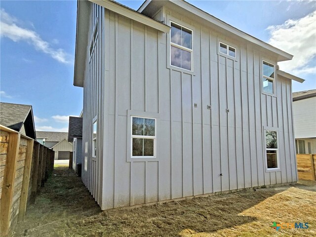 view of property exterior featuring board and batten siding and fence