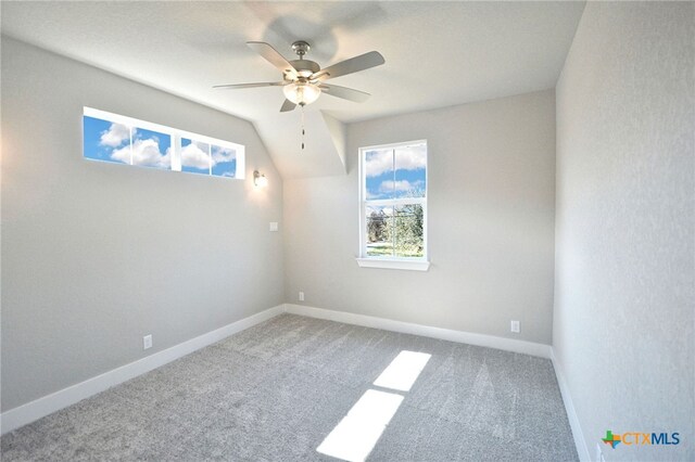 carpeted empty room with a wealth of natural light, baseboards, and ceiling fan