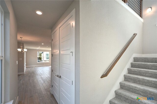 stairway featuring recessed lighting, wood finished floors, baseboards, and a chandelier