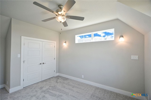 unfurnished bedroom featuring ceiling fan, baseboards, carpet, vaulted ceiling, and a closet