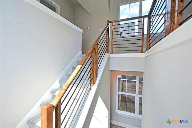 stairway featuring a towering ceiling