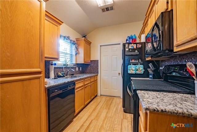 kitchen featuring decorative backsplash, light stone countertops, black appliances, and light hardwood / wood-style floors