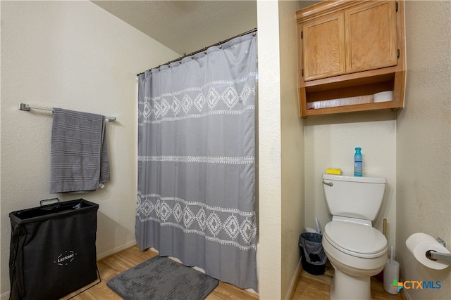 bathroom with hardwood / wood-style floors, a textured ceiling, toilet, and a shower with curtain