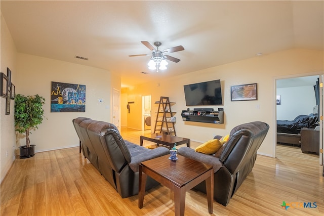 living room with ceiling fan, light hardwood / wood-style flooring, lofted ceiling, and washer / dryer