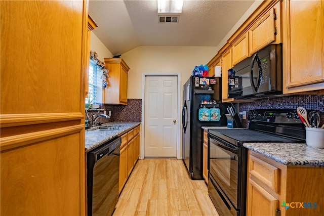 kitchen with tasteful backsplash, sink, black appliances, light hardwood / wood-style flooring, and lofted ceiling