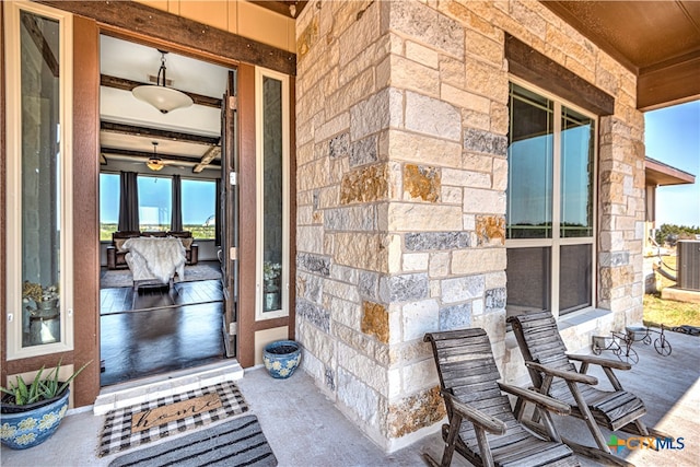 view of exterior entry featuring central air condition unit and covered porch