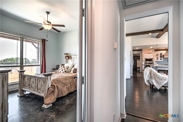 bedroom with dark wood-type flooring, beamed ceiling, and ceiling fan