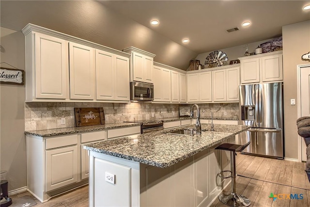 kitchen with visible vents, decorative backsplash, light wood-type flooring, a sink, and appliances with stainless steel finishes