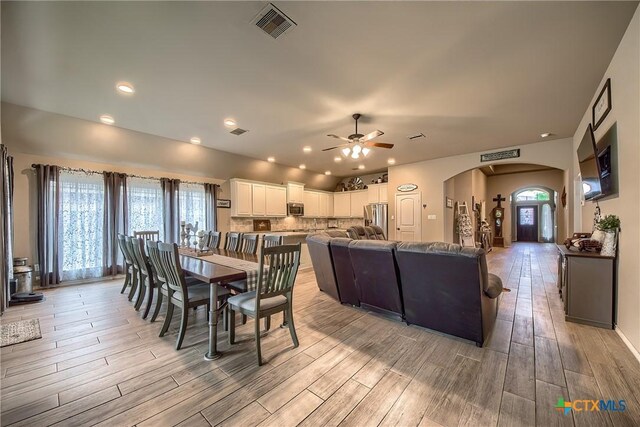 dining area featuring visible vents, ceiling fan, recessed lighting, arched walkways, and light wood finished floors