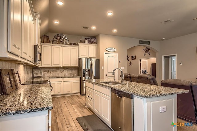 kitchen featuring a sink, appliances with stainless steel finishes, tasteful backsplash, and open floor plan