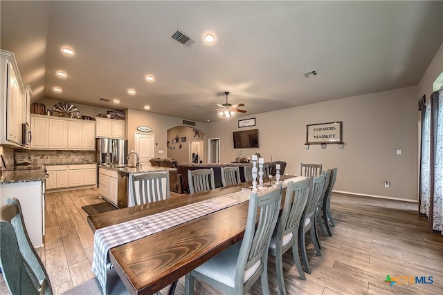 dining room featuring visible vents, a ceiling fan, arched walkways, and light wood-type flooring