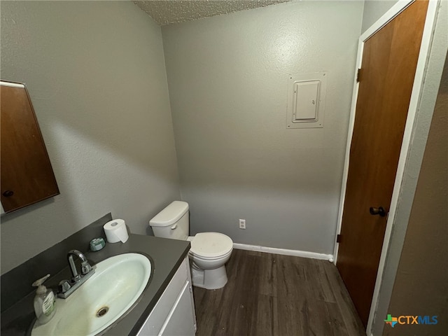 bathroom with hardwood / wood-style floors, a textured ceiling, toilet, and vanity