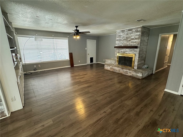 unfurnished living room featuring a brick fireplace, a textured ceiling, dark hardwood / wood-style floors, and ceiling fan