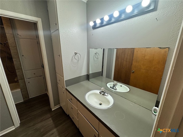 bathroom with wood-type flooring, vanity, and bathtub / shower combination