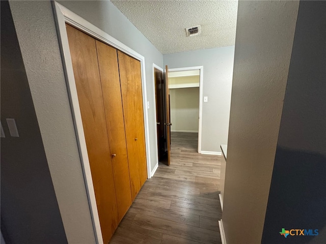 hallway with wood-type flooring and a textured ceiling