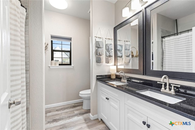 312 Holly Ave, Luling, TX 78648 - bathroom featuring double vanity, wood finished floors, and curtained shower