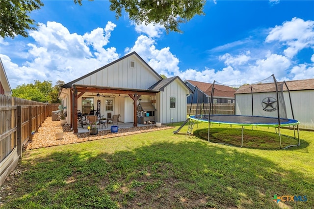 312 Holly Ave, Luling, TX 78648 - rear view of property featuring board and batten siding, a trampoline, a patio area, a fenced backyard, and a ceiling fan