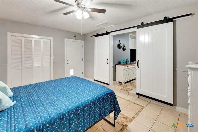 2812 Curlew St, Victoria, TX 77901 - bedroom with a barn door, light tile patterned floors, a textured ceiling, and a ceiling fan