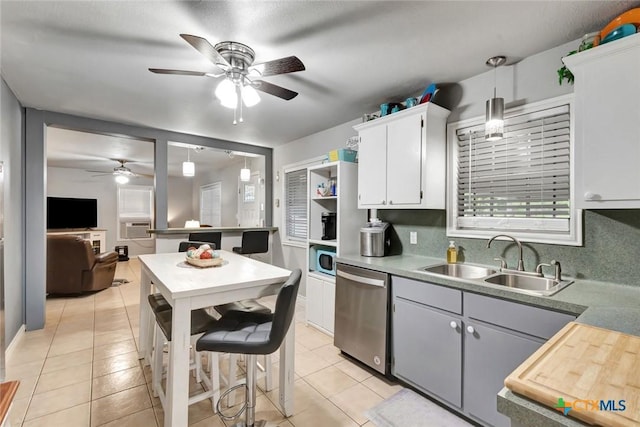 2812 Curlew St, Victoria, TX 77901 - kitchen featuring stainless steel dishwasher, a ceiling fan, light tile patterned floors, hanging light fixtures, and white cabinetry