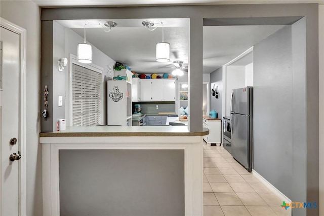 2812 Curlew St, Victoria, TX 77901 - kitchen with freestanding refrigerator, light tile patterned flooring, white cabinetry, a peninsula, and decorative light fixtures