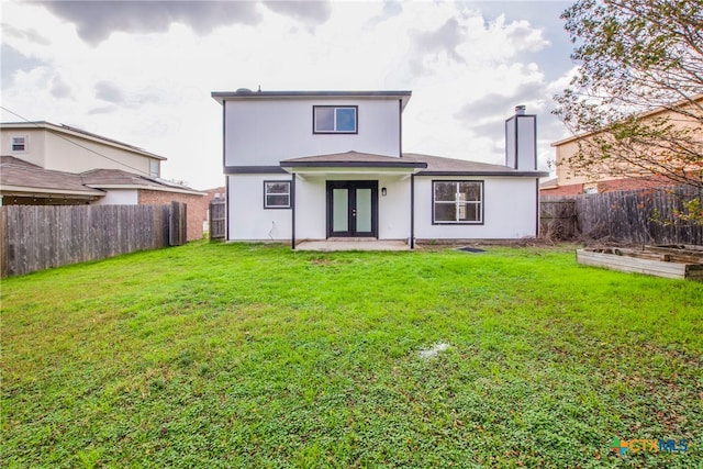 back of house with french doors and a yard