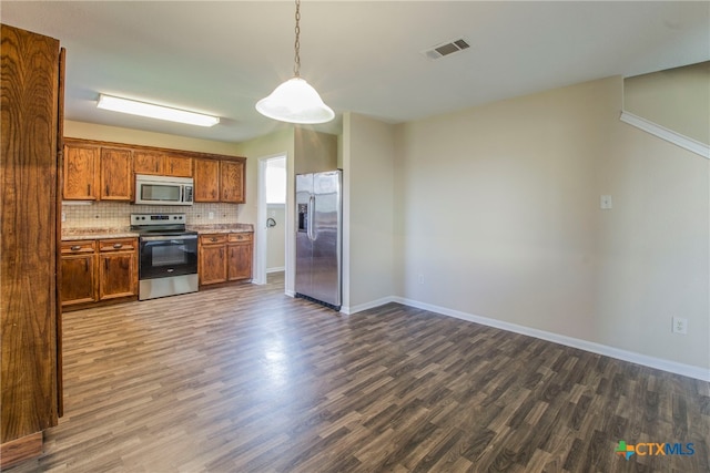 kitchen with dark hardwood / wood-style floors, decorative backsplash, hanging light fixtures, and appliances with stainless steel finishes